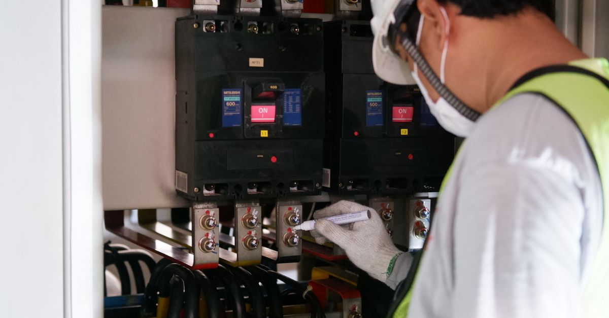 Teknisi memeriksa panel listrik untuk kajian energi