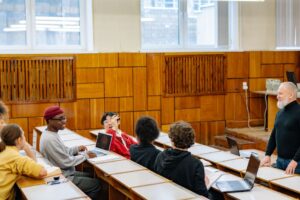 Mahasiswa berdiskusi dengan dosen di kelas sebagai simbol perencanaan dan dukungan kompetensi ISO 21001