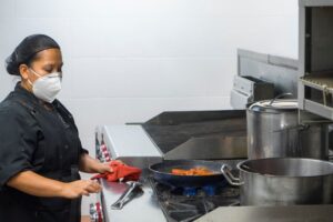 Juru masak bekerja dengan masker pelindung di dapur komersial sebagai simbol kompetensi dan training ISO 22001