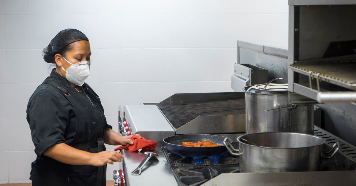 Juru masak bekerja di dapur komersial bersertifikat sebagai ilustrasi manfaat sertifikasi HACCP